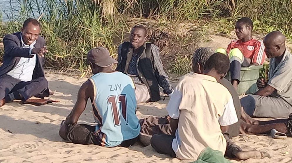 Men sitting on the ground having a discussion.