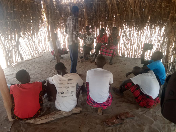 Men studying the Bible in a thatch hut